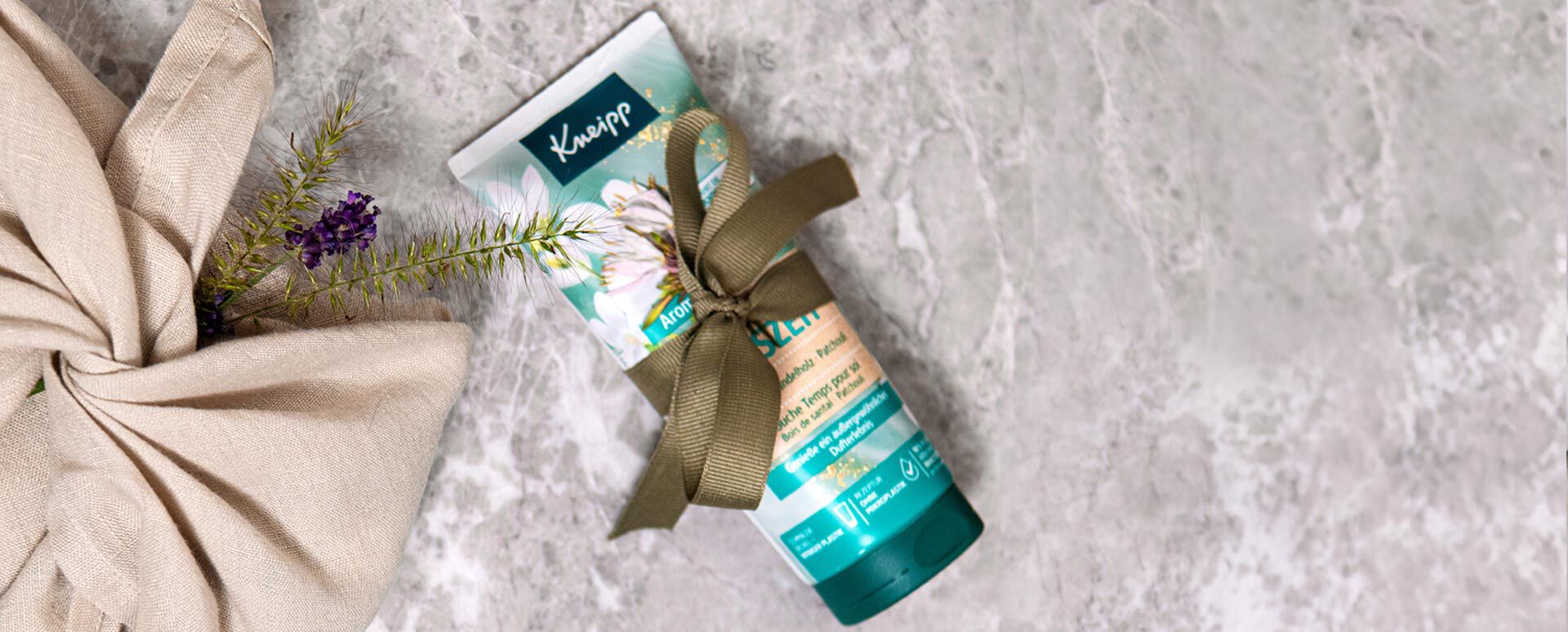 Kneipp Dusche Kleine Auszeit mit grüner Geschenkschleife liegt auf Marmorplatte